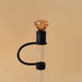 Decorative lamp with a clear glass base, black accents, and an amber-colored bulb on a beige background.