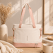Beige and pink tote bag on a wooden surface with a vase and books in the background