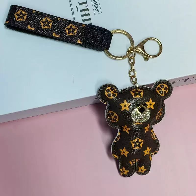 Black bear-shaped keychain with gold star patterns on a pink surface