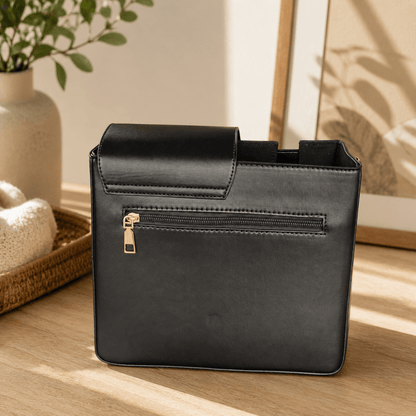 Black leather handbag with gold zipper on a wooden surface with a neutral background