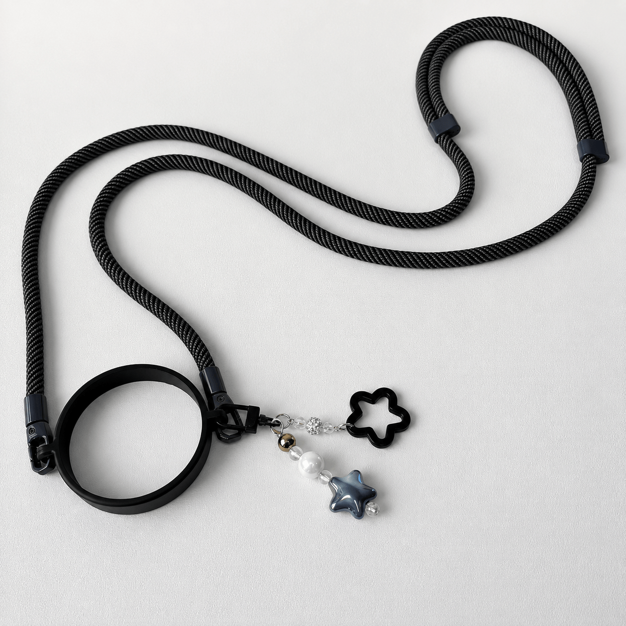 Black rope necklace with star-shaped charms on a light gray background