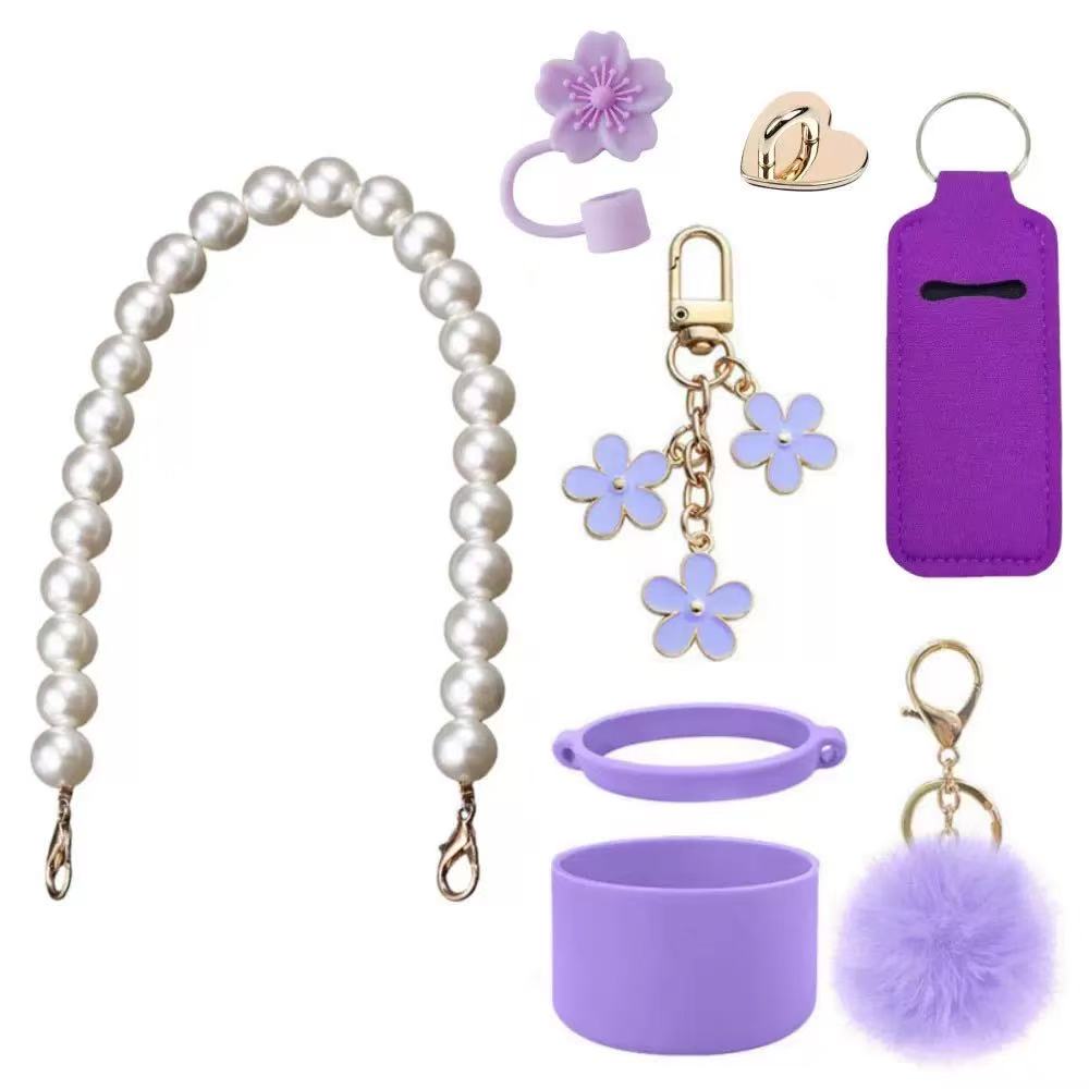 Cute tumbler accessory set including a pearl handle strap, silicone boot, flower straw cap, pom-pom charm, and decorative cup accessories designed to personalize tumblers and water bottles.