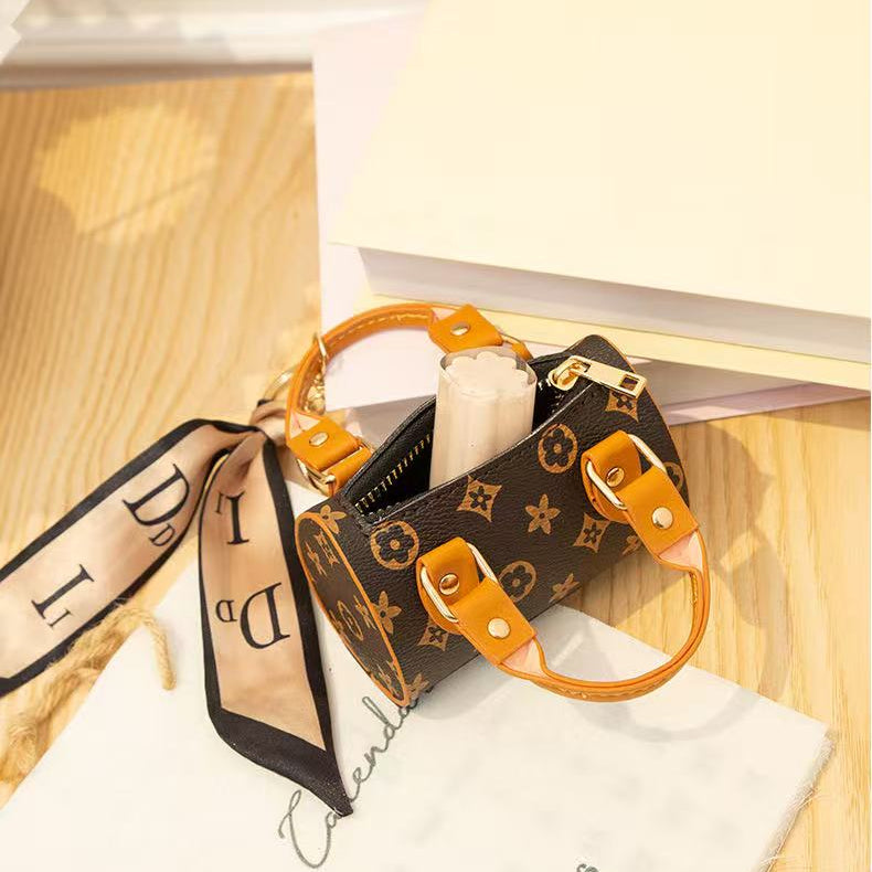 Designer handbag with monogram pattern and orange accents on a wooden surface