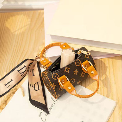 Designer handbag with monogram pattern and orange accents on a wooden surface