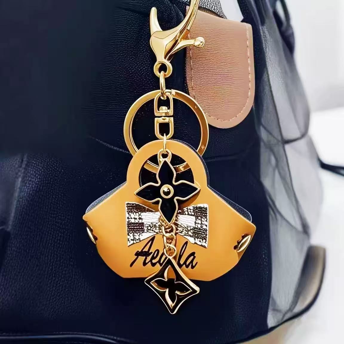 Gold keychain with decorative elements attached to a black bag.