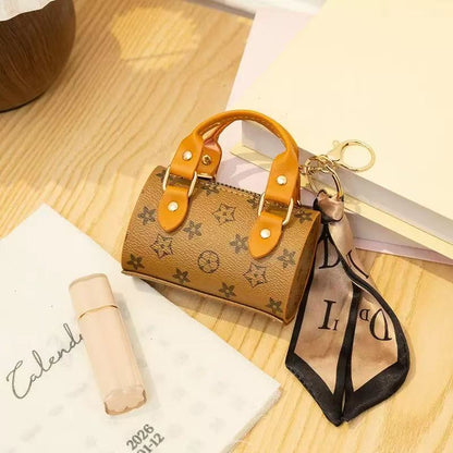 Miniature handbag keychain with brand logo on a wooden surface
