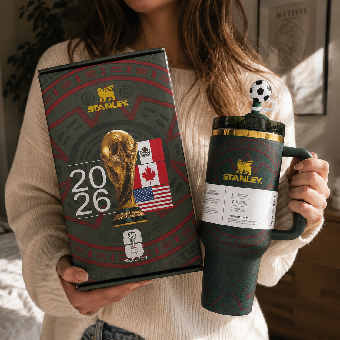 Person holding a Stanley mug and notebook with 2026 World Cup design.