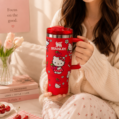 Person holding a red Stanley tumbler with Hello Kitty design in a cozy indoor setting.