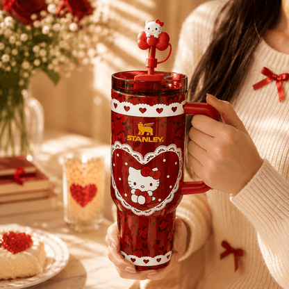 Person holding a red Stanley tumbler with Hello Kitty design, surrounded by festive decor.