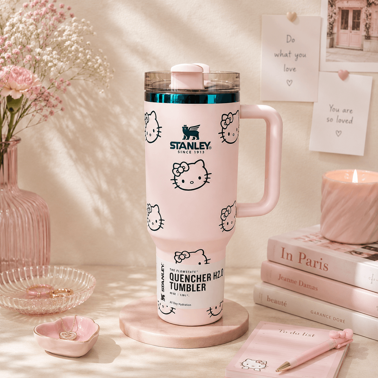 Pink Stanley tumbler with Hello Kitty designs on a decorative table.