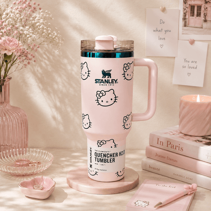 Pink Stanley tumbler with Hello Kitty designs on a decorative table.