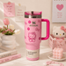 Pink Stanley tumbler with Hello Kitty designs on a decorative surface with flowers and books.