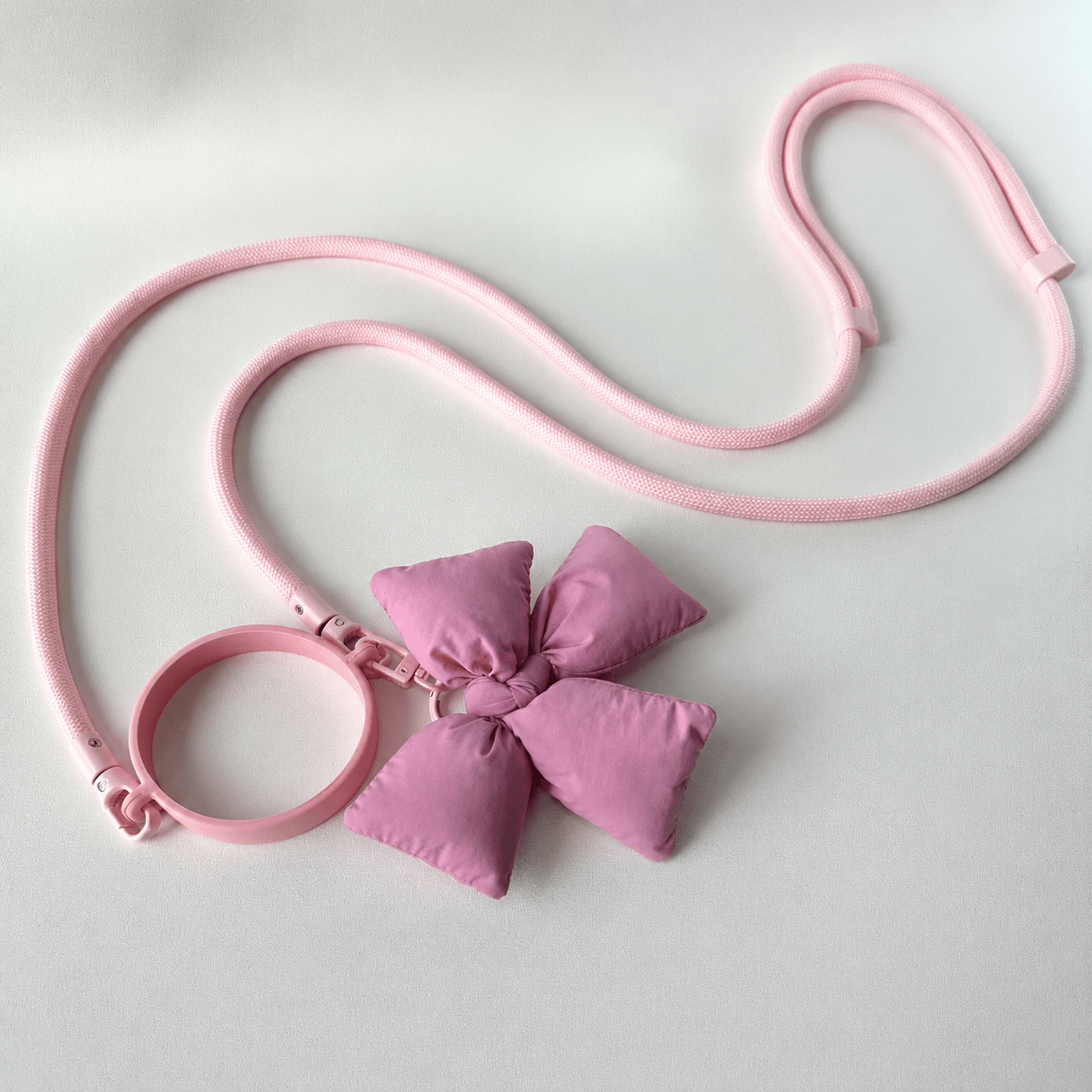 Pink dog leash with a large bow on a light gray background