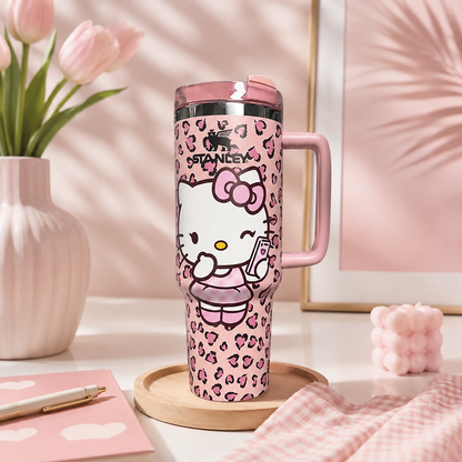 Pink travel mug with Hello Kitty design on a desk with flowers and stationery.
