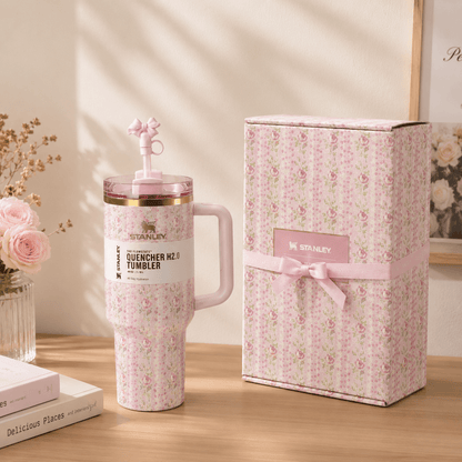 Pink tumbler with floral pattern and matching gift box on a wooden surface.