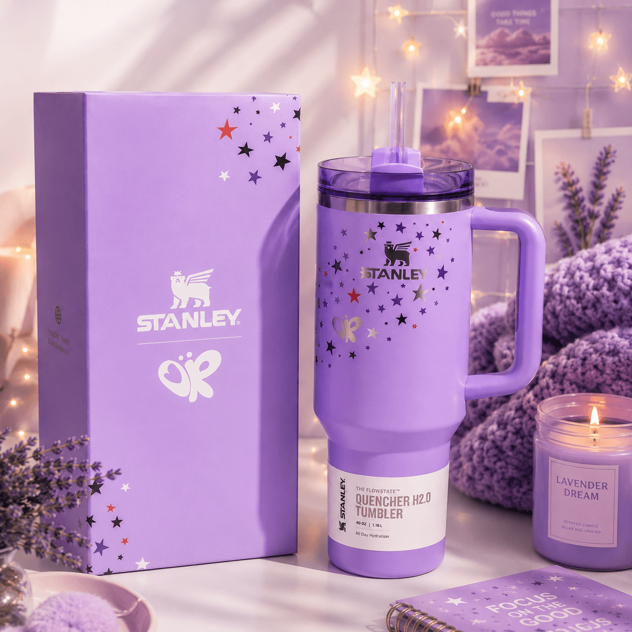Purple Stanley tumbler with decorative stars on a table with a matching box and lavender-themed decor.