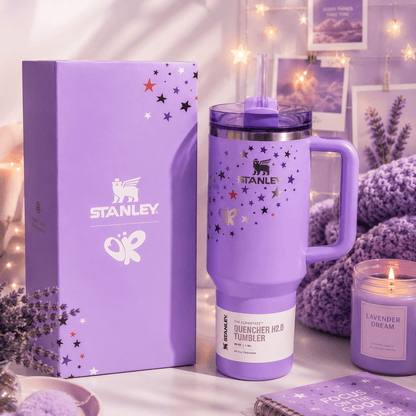Purple Stanley tumbler with decorative stars on a table with a matching box and lavender-themed decor.