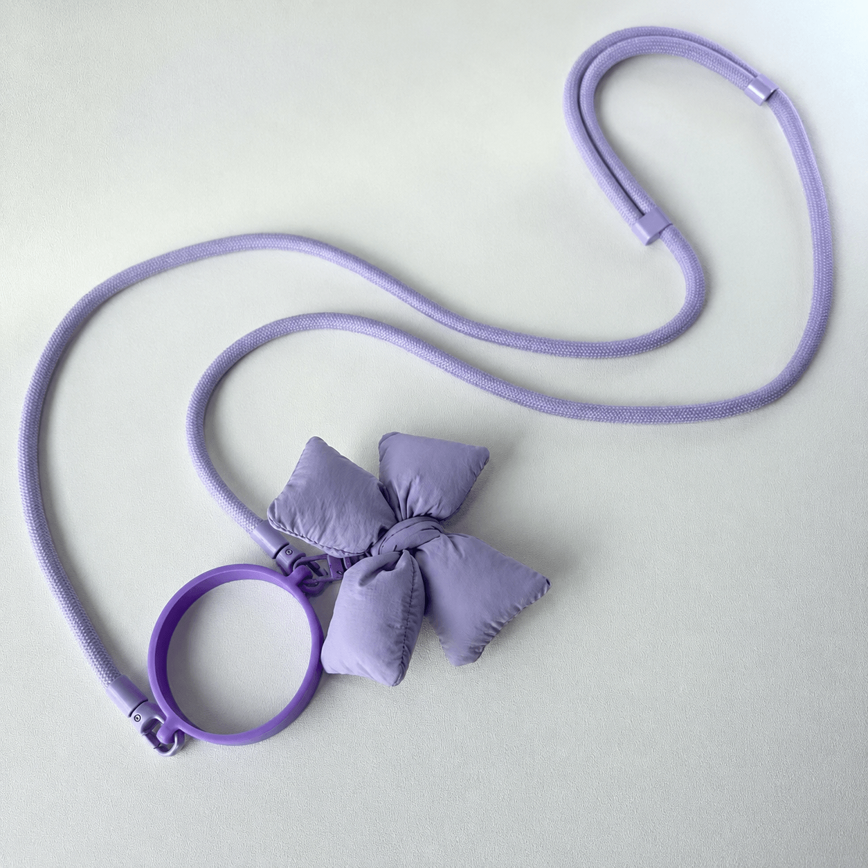 Purple dog leash with a bow on a light gray background