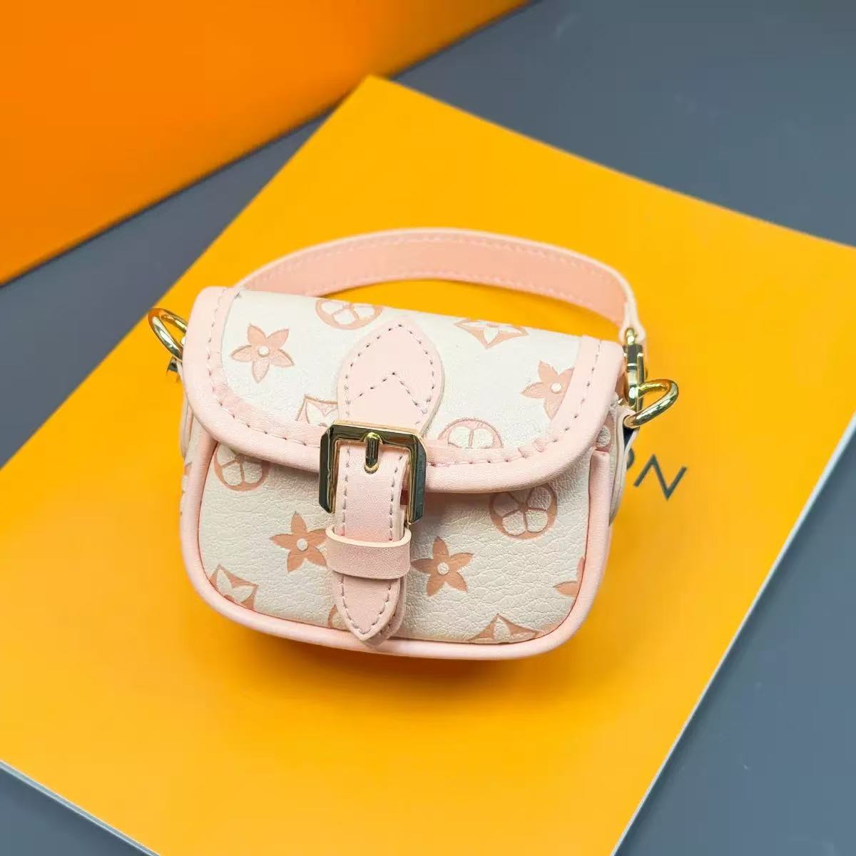 Small pink and beige handbag with floral pattern on a colorful geometric background