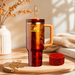 Stanley mug with a pineapple spout on a wooden surface with a warm background