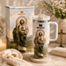 Stanley mug with religious iconography on a decorative table with flowers and candles.