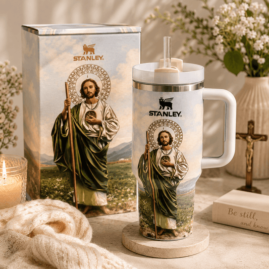 Stanley mug with religious iconography on a decorative table with flowers and candles.