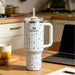 Stanley mug with star pattern on a kitchen counter with laptop and lemons