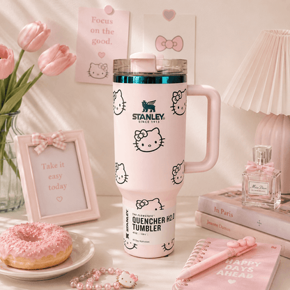 Pink Stanley tumbler with Hello Kitty designs on a table with flowers, books, and a donut.