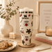 Stanley tumbler with 'Stranger Things' designs on a table with cookies and books.
