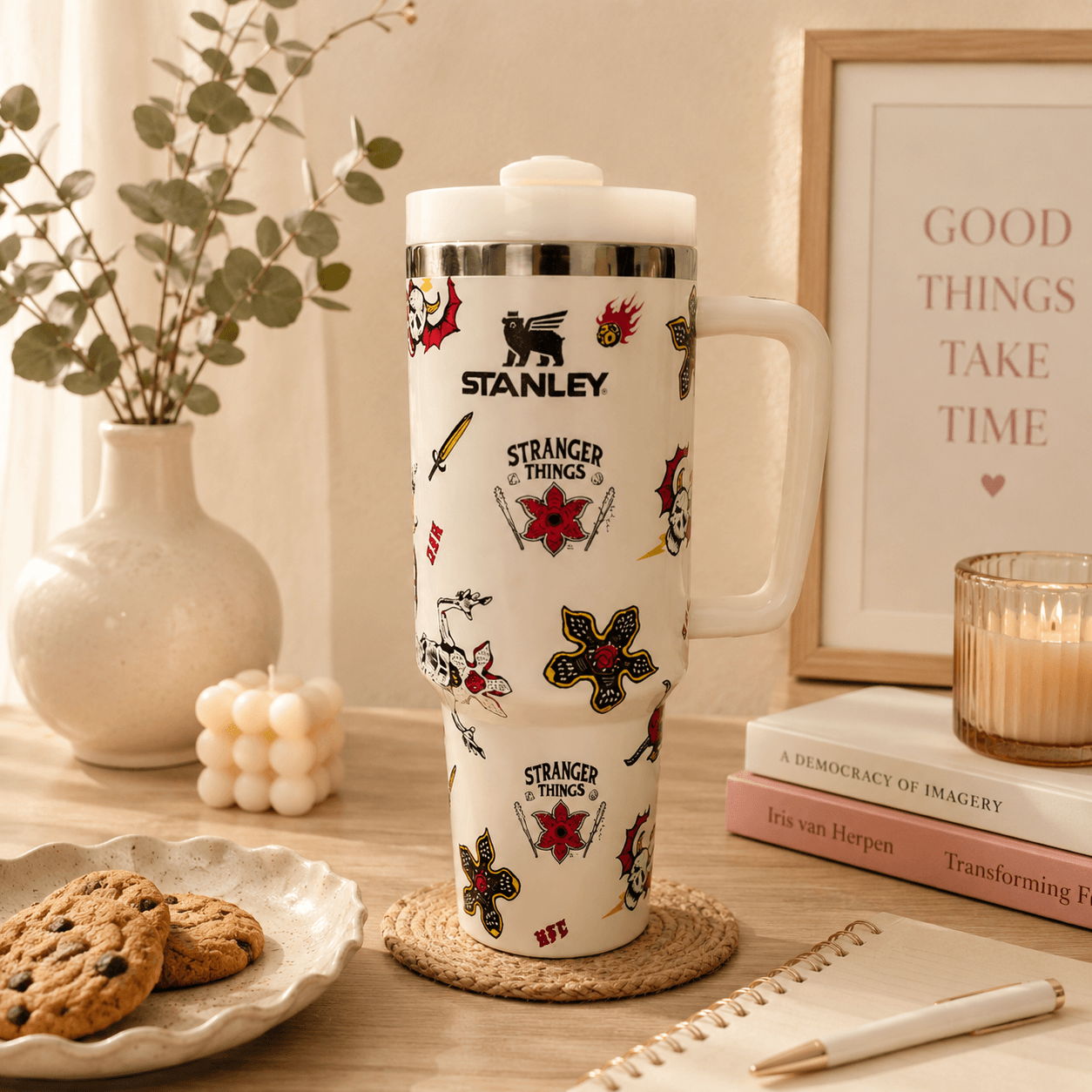 Stanley tumbler with 'Stranger Things' designs on a table with cookies and books.