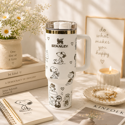 Stanley tumbler with cartoon character design on a table with books and flowers