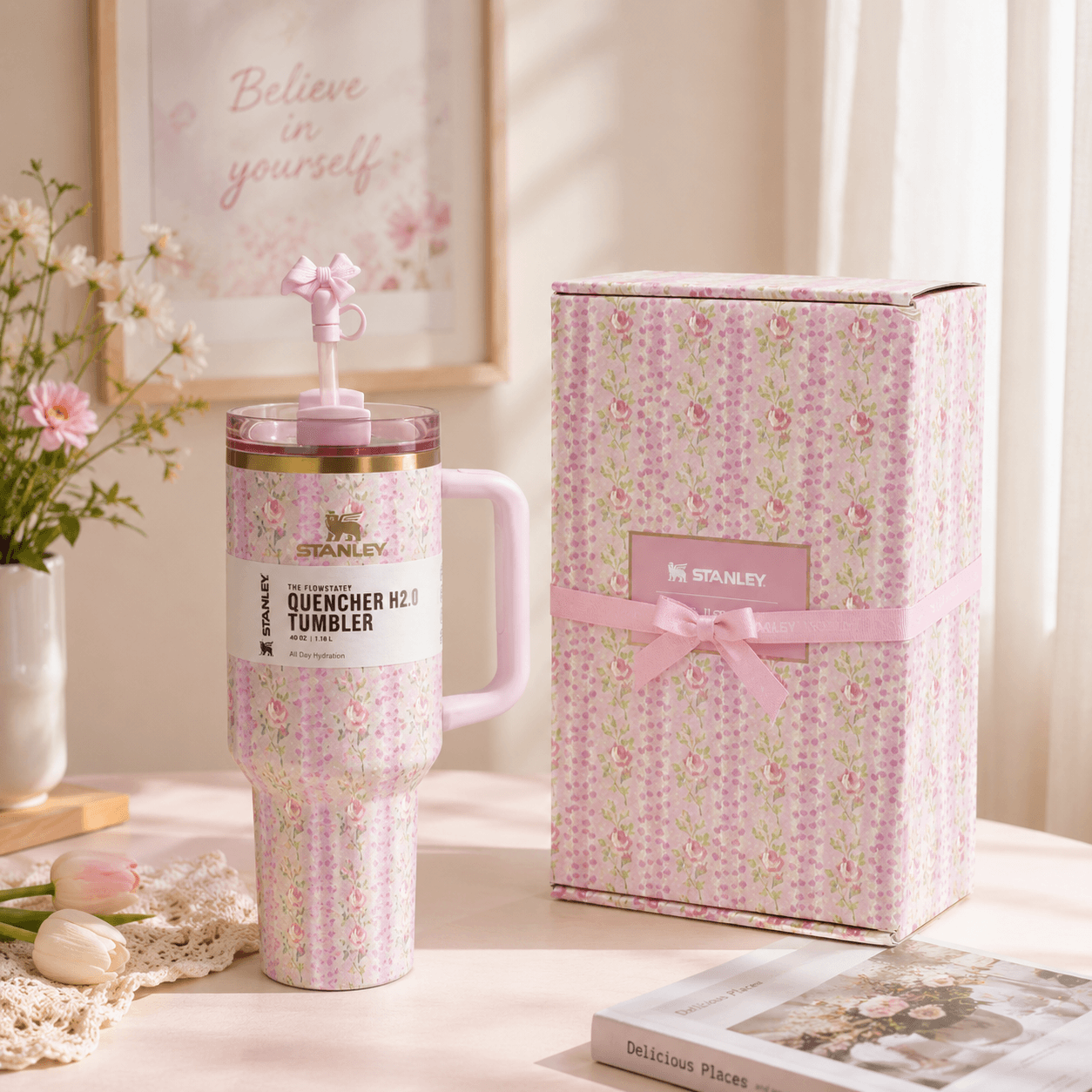 Stanley tumbler with floral design next to its packaging on a decorative surface.