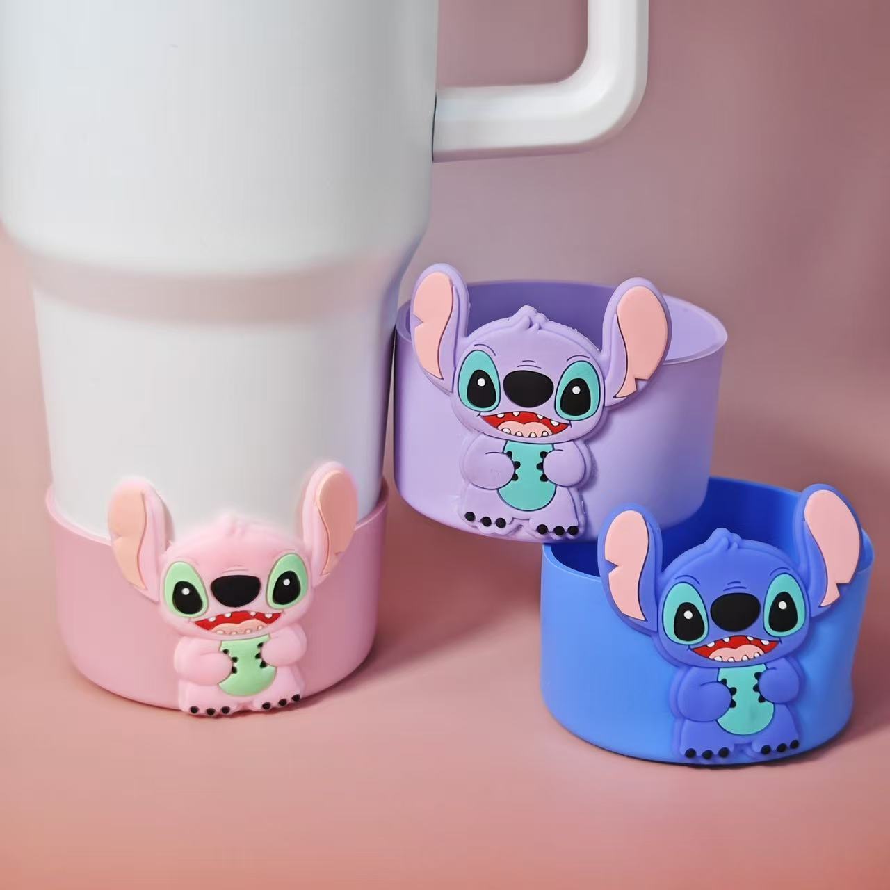 Three cartoon character cups in pink, purple, and blue on a pink background