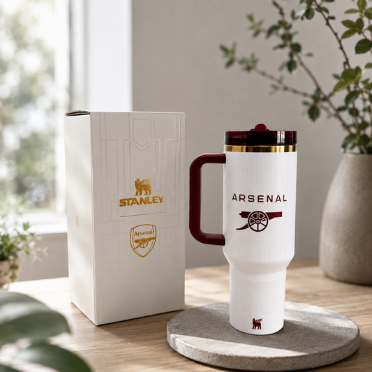 White travel mug with Arsenal logo and Stanley packaging on a wooden surface.