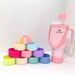 Stanley 40oz insulated tumbler with pink bow design, matching pink shoulder strap, pastel accessories and colorful cup sleeves