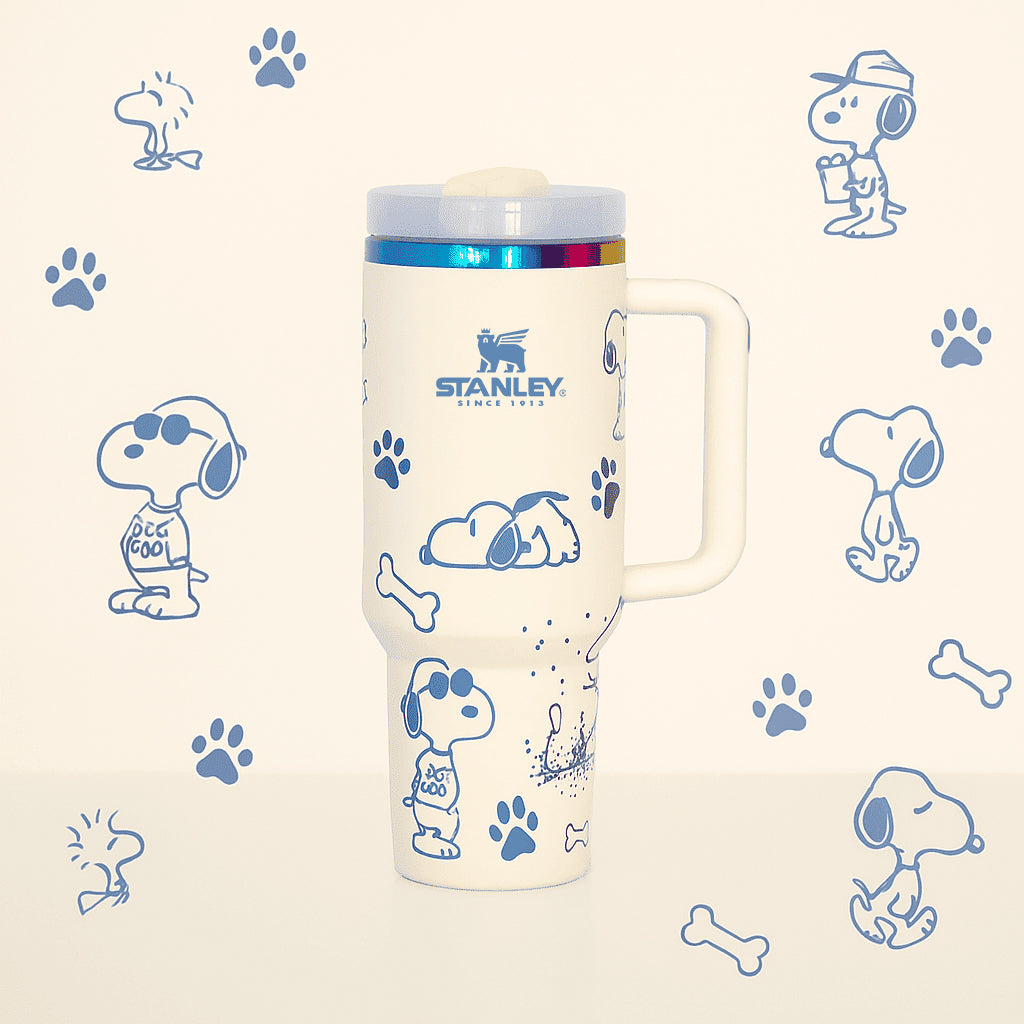 Stanley 40oz insulated tumbler featuring Snoopy illustrations, blue paw prints and bone icons, white body with white ergonomic handle