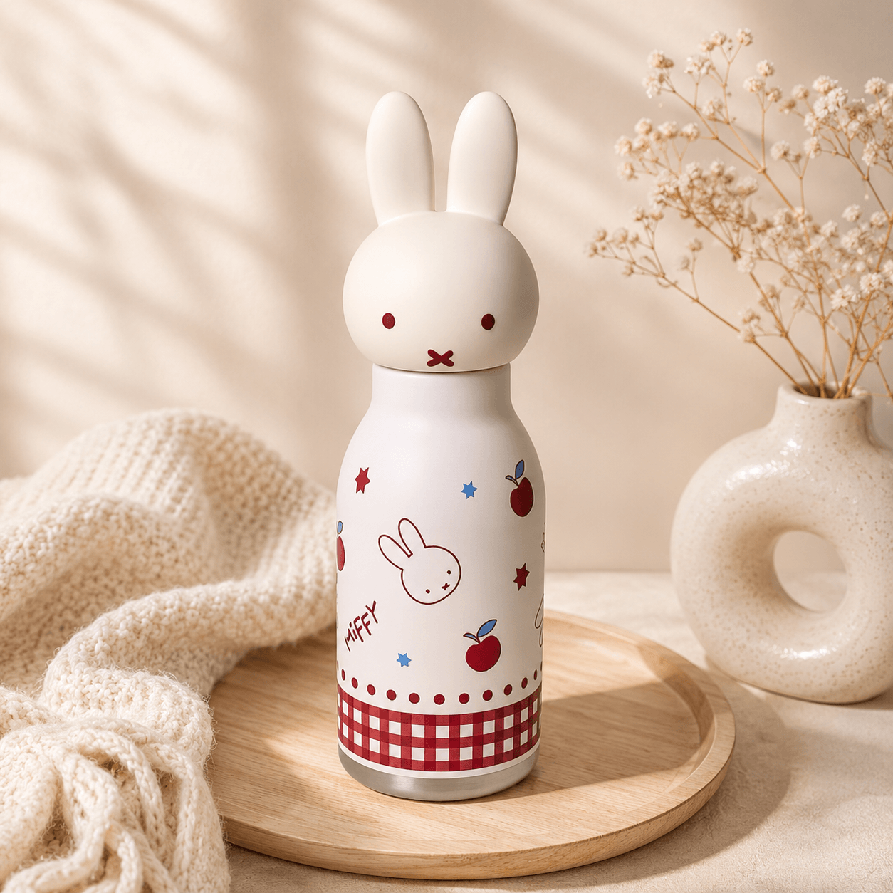 White bunny-shaped bottle with colorful designs on a wooden surface with a neutral background